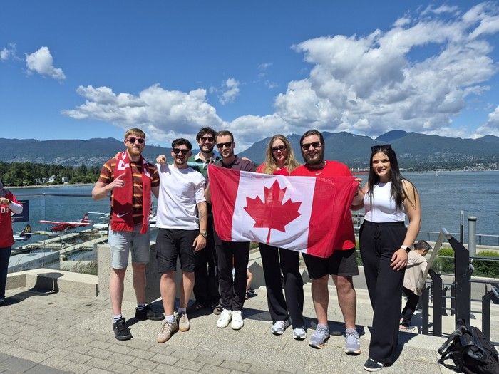 Hayes employees from the downtown Vancouver office stand outside with a Canadian flag on a sunny day.