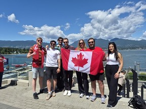 Hayes employees from the downtown Vancouver office stand outside with a Canadian flag on a sunny day.