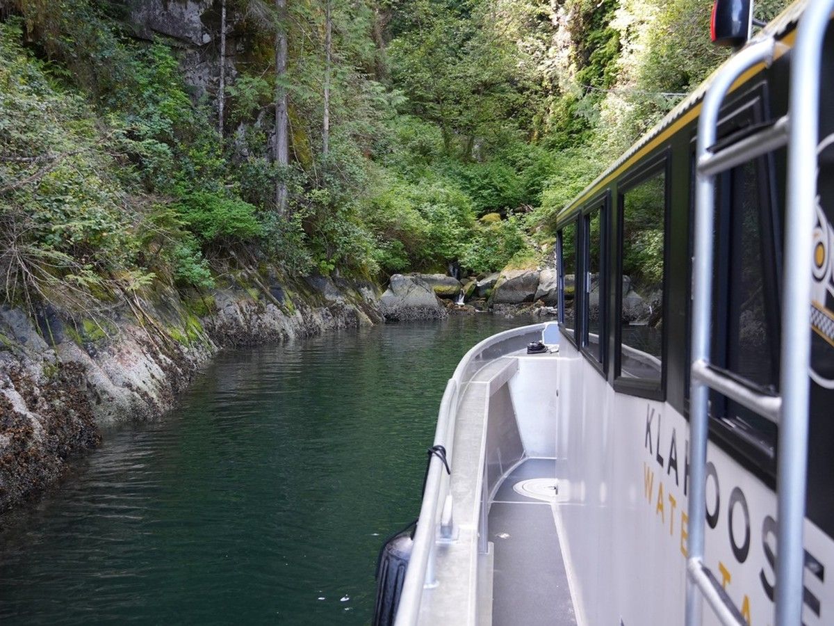 Boat glides into a hidden cache in the rock face on the coast of Desolation Sound.