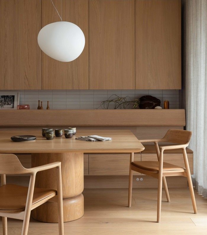  Oak cabinetry, a built-in banquette and finely crafted furniture create a warm, understated dining space at Seawall House, interior design by Falken Reynolds.