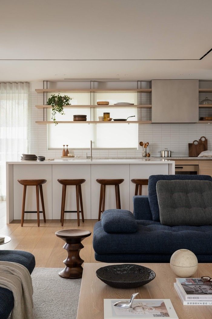  The open-plan kitchen and living area at Seawall House uses a restrained palette of oak, white cabinetry and natural textures, interior design by Falken Reynolds.