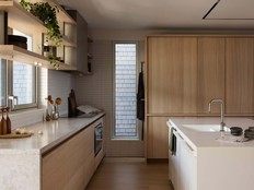 Natural oak cabinetry, stone surfaces and integrated storage bring warmth and practicality to the Seawall House kitchen, interior design by Falken Reynolds.