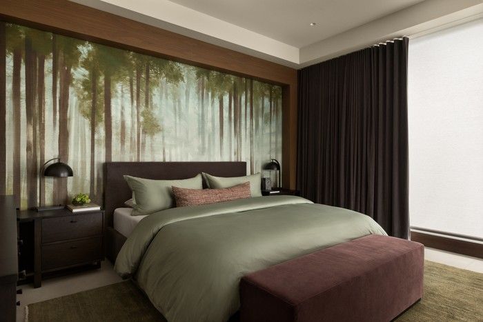 The forest view on the wallpaper in the primary bedroom provides a juxtaposition for the ocean view seen from the seating area. A TV is concealed in the wood structure – it is raised for viewing and when not in use, retracts back into the cabinetry.