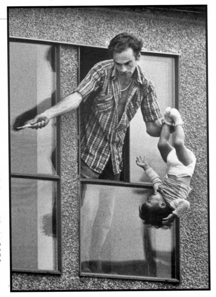  A man dangles his two-year old boy in this dramatic 1985 NNA winning photo by Ralph Bower.