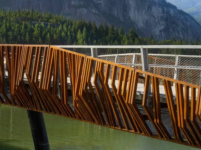 Weathered steel references Squamish's railway history and the vertical rhythm of the surrounding forest.