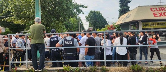  Police monitor dozens of customers of Apadana Currency Exchange in North Vancouver as they demand to know where their money went, on Aug. 16, 2026