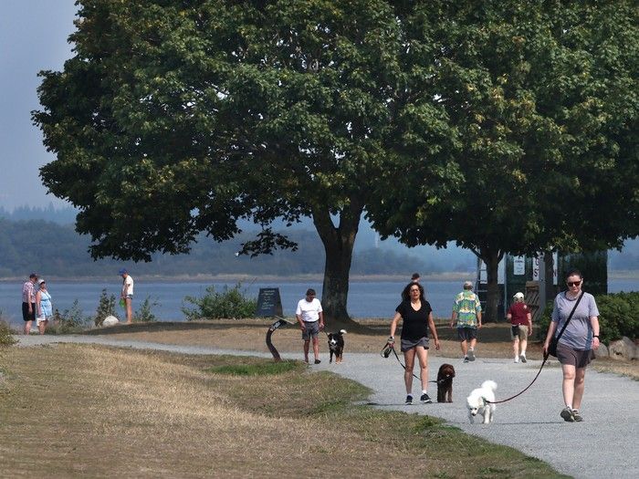  people take a stroll at crescent beach in south surrey on aug. 5, 2026 after a yellow warning has been issued for deteriorating air quality due to forest fires around b.c.