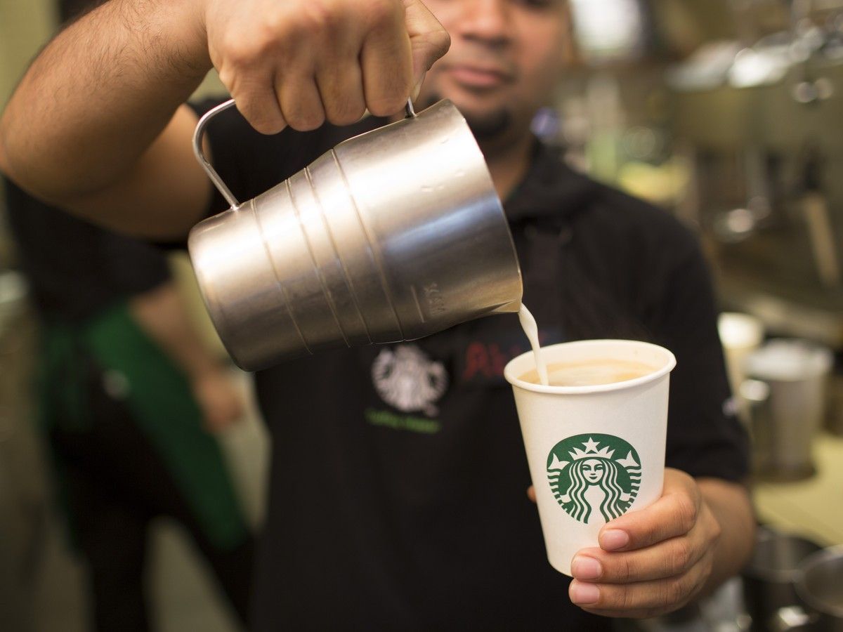 A Starbucks employee pours milk into a coffee cup inside a Starbucks store in London, U.K.