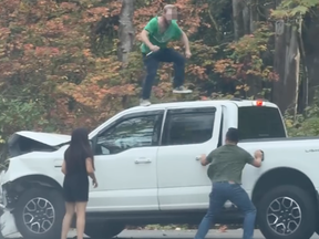 A man on top of a truck with a knife.
