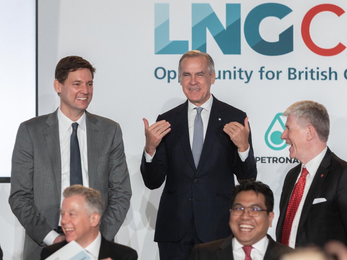 Prime Minister Mark Carney (centre) jokes about standing on a podium so he isn't dwarfed by the 6-foot-7 B.C. NDP Leader Premier David Eby (left) as executives of companies involved in LNG Canada laugh along at the announcement that Phase 2 of the Kitimat liquefaction plant will go ahead, in Vancouver on September 29, 2026