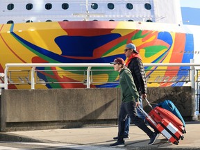 People walk with their suitcases outside the Canada Place cruise ship terminal on Monday, Oct. 12, 2026, as the season ends with a record number of passengers.