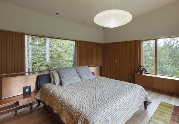 On the second floor, sleeping quarters feel set into the tree canopy, with built-in drawers tucked into deeper pockets created by angled exterior walls. Etched copper screens bearing a Japanese floral motif – by Vancouver printmaker Peter Braune of New Leaf Editions – flank a bed with floating arbutus burl side tables. Motorized blackout and privacy blinds disappear into ceiling pockets around the windows.