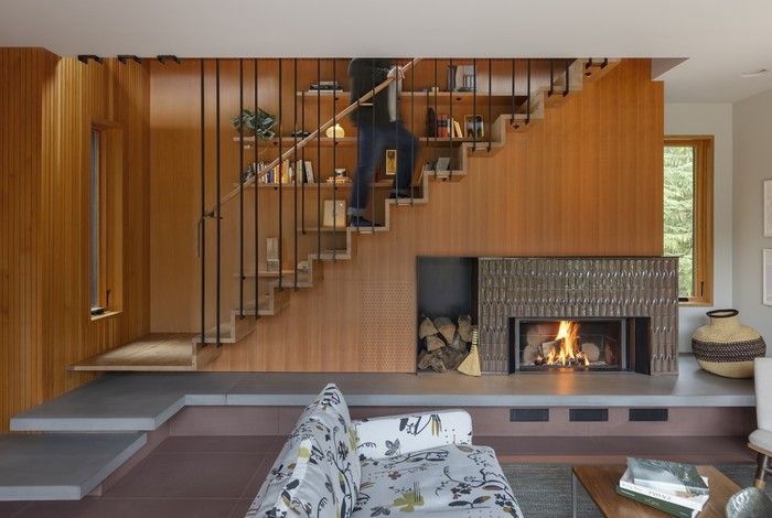 A fireplace in textured tile (MADE Chinois from Ann Sacks) sits alongside a custom rail system (fabricated by Metal Mart) that supports a floating arbutus wood staircase. The metal rods rise to the second floor, becoming a guardrail upstairs.