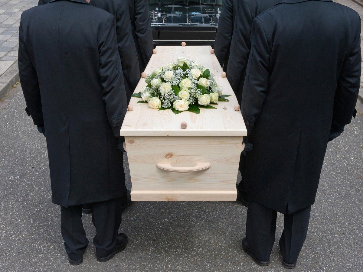 Bearers a carrying a coffin into a car