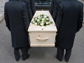 Bearers a carrying a coffin into a car