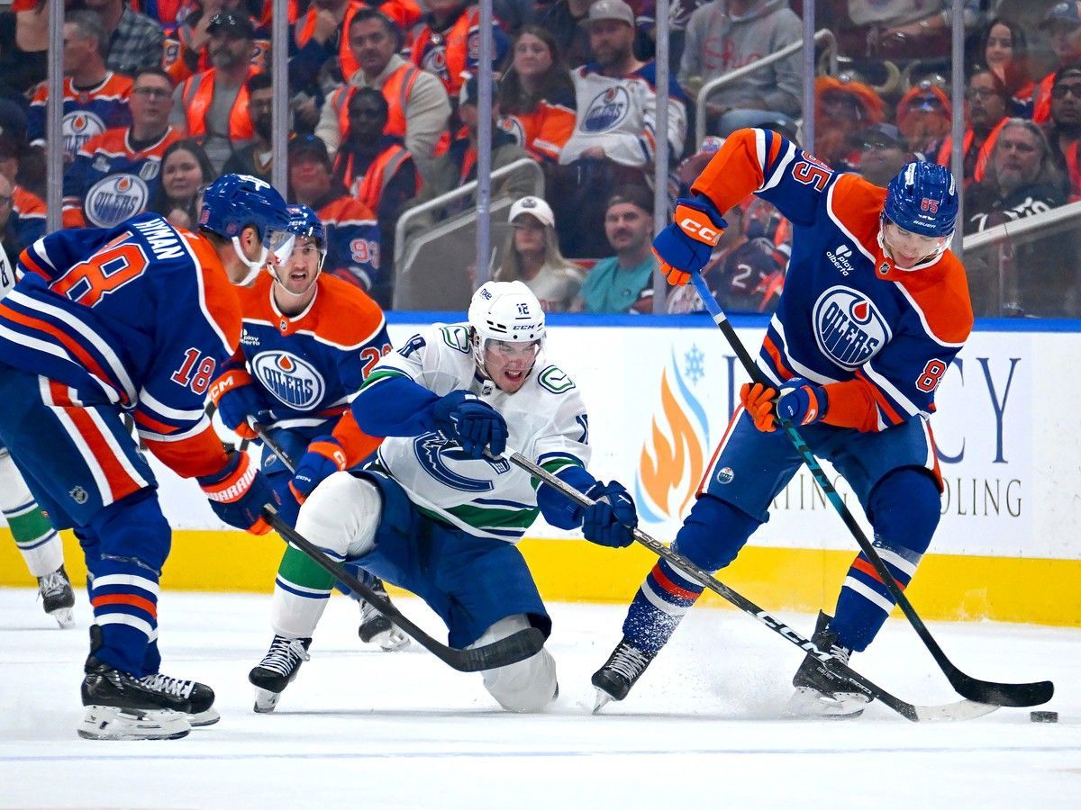 Drew O'Connor of the Canucks battles for the puck against Shakir Mukhamadullin of the Oilers during the first period