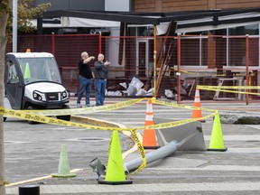 Twisted lamposts, police tape and traffic cones line a sidewalk