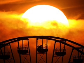 People sit in a gondola of a Ferris wheel as the sun sets behind them at a fair in the northern German city of Hanover on May 8, 2011 (JULIAN STRATENSCHULTE/AFP/Getty Images)