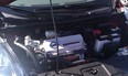 The "engine" bay of a Nissan Leaf; inverter atop motor, 12 v accessory battery on far right.