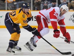 Ryan Ellis #49 of the Nashville Predators checks Drew Miller #20 of the Detroit Red Wings during an NHL game at the Bridgestone Arena on December 26, 2011 in Nashville, Tennessee. (Photo by John Russell/NHLI via Getty Images)