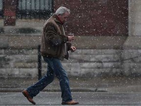 A pedestrian walks westward on University Avenue in front of the Windsor Armouries in a flurry of snowfall, Tuesday, Dec. 27, 2011. (DAX MELMER / The Windsor Star)