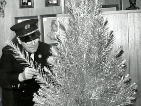 HISTORIC-DEC.15/1961-Artificial Christmas trees made of aluminum are being sold in large numbers around Windsor this year. Fire Inspector Phil Murphy shows the recommended type of direct lighting equipment. (The Windsor Star-FILE)