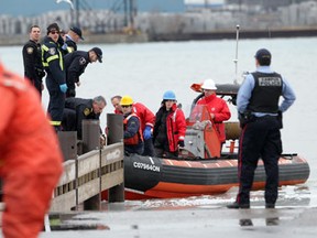 Representatives from several agencies assist in removing a woman Monday from the icy waters of the Detroit river at the foot of Chewiit Street.The woman later died. (Photo By: Jason Kryk)