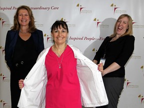 Hotel-Dieu Grace Hospital worker Carla Soulliere, centre, demonstrates a WeightWatchers "reveal" following an award presentation by WeightWatchers Andrea Bradford-Lambert, right, to Toni Janik, left, director of health science library at Hotel-Dieu Grace Hospital January 19, 2012. (Photo By: Nick Brancaccio)