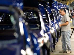 A Ford Motor Co. employee inspects 2012 Focus vehicles moving down the assembly line at the Michigan Assembly Plant. Photo by Jeff Kowalsky, Bloomberg