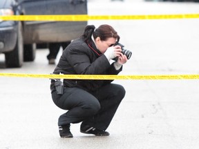 A Windsor Police forensic identification officer photographs the scene after an elderly woman was struck by a vehicle on Felix Avenue in Windsor, Ontario on February 22, 2012. Traffic was blocked in both directions while police investigated the scene. (Photo By: Jason Kryk)
