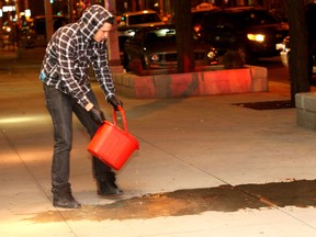 Windsor, Ontario. February 4, 2012.  A man pours a bucket of water on drops of blood on the sidewalk from a man who fell from the second floor level of a downtown hotel late Sat. Feb. 4, 2012.  The man sustained injuries to his head and was taken to hospital by ambulance. (REBECCA WRIGHT/The Windsor Star)