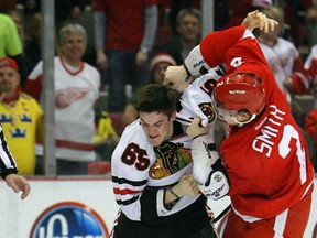 Andrew Shaw #65 of the Chicago Blackhawks takes a punch to the head from Brendan Smith #2 of the Detroit Red Wings during their NHL game at Joe Louis Arena on March 4, 2012 in Detroit, Michigan. (Photo by Dave Sandford/Getty Images)
