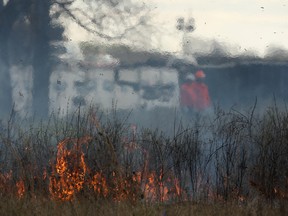 Workers conduct a controlled burn of prairie grass between Chappus Street and the E.C. Row Expressway in Windsor, Ont. on Mar. 26, 2012.