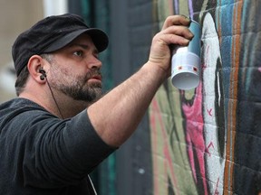 A graffit artist from Detroit, known as Fel3000ft, paints in an alley south of Maiden Lane between Pelissier Street and Ouellette Aveneu, Sunday, April 1, 2012. (DAX MELMER/The Windsor Star)