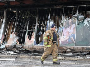 A firefighter walks by the remains of Dollarama's storefront. (Dan Janisse / The Windsor Star)