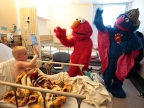 Tonsillectomy patient Benny Fehr, 4, waves to Elmo and Super Grover during their visit to the pediatrics ward of Windsor Regional Hospital on April 17, 2012. (Jason Kryk / The Windsor Star)