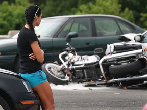 A young woman sits near the scene of a serious motorcycle accident Thursday, June 21, 2012, on EC Row eastbound in Windsor, Ont. The accident occurred just east of Lauzon Parkway.