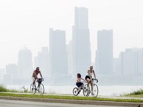A family rides bicycles on Windsor's riverfront while a smoggy Detroit skyline looms behind them in this 2007 file photo. (Tyler Brownbridge / The Windsor Star)