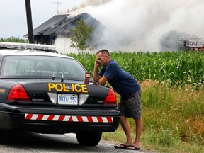 A resident of a home identified as Brent by a neighbour,  makes a phone call while giving a statement to Lakeshore OPP as Lakeshore firefighters try to control the flames at 1005 Lakeshore Road 101 Tuesday July 3, 2012.  Nobody was home at the time of the fire.  (NICK BRANCACCIO/The Windsor Star)