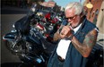 Hundreds of motorcyclists descended into Little Italy in Windsor, Ont., for an Erie Street bike rally, Thursday, July 26, 2012. The rally is part of Bikefest, which is in conjunction with the 24th Ontario Provincial H.O.G. Rally. Here, Mark Woltz lights up a cigar in front of his Harley. (Dax Melmer/The Windsor Star)