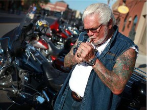 Hundreds of motorcyclists descended into Little Italy in Windsor, Ont., for an Erie Street bike rally, Thursday, July 26, 2012. The rally is part of Bikefest, which is in conjunction with the 24th Ontario Provincial H.O.G. Rally. Here, Mark Woltz lights up a cigar in front of his Harley. (Dax Melmer/The Windsor Star)