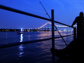 Fishermen hang out on the Detroit River following a bomb threat that closed the Ambassador Bridge to Canada Monday, July 17, 2012. Someone phoned in a threat from the U.S. side of the busy international border crossing around 7:20 p.m. (AP Photo/Detroit News, Elizabeth Conley)