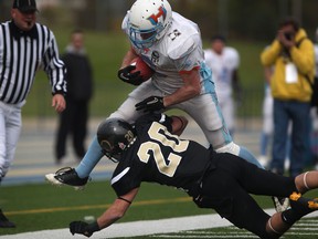 Windsor's Tyler Bremner, bottom, tackles Hamilton running back Ryan Kotar at Alumni Field. (DAX MELMER / The Windsor Star)