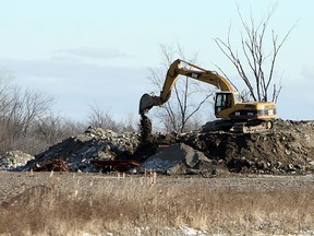 A track hoe moves material behind a home on Howard Avenue near Windsor on Wednesday, Dec. 28, 2011. The Jones Group, which owns the lot, may be forced to pay up to $4 million in fines for using the site as an illegal dump. (TYLER BROWNBRIDGE / The Windsor Star)