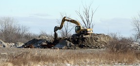 A track hoe moves material behind a home on Howard Avenue near Windsor on Wednesday, Dec. 28, 2011. The Jones Group, which owns the lot, may be forced to pay up to $4 million in fines for using the site as an illegal dump. (TYLER BROWNBRIDGE / The Windsor Star)