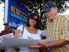 Veronika Nagy, left, and Ron Varley sign a petition as about  60 area residents and concerned viewers gather at Cogeco Cable's Dougall Road studios to voice their displeasure with the decision to drop Bill Kelso, Brian Trenholm and Domenic Papa from their Windsor Spitfires broadcasts August 23, 2012. (NICK BRANCACCIO/The Windsor Star)