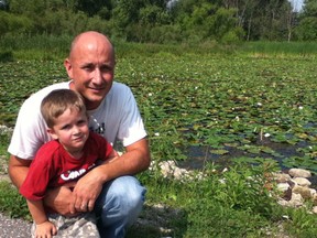 Essex Resident Craig Weglarz and his three-year-old son Henry visit Sadler's Pond often. It's a great habitat for turtles and fish. Weglarz thinks the pond, which is full of lily pads and garbage, is threatened because of its low water level. He asked the town to clean it up and consider dredging it. (MONICA WOLFSON/ The Windsor Star)