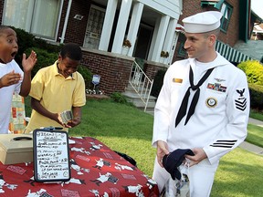 Joshua Smith and Dwayne Durant (right) react after AM1 Robert Wawro presented them with $250 from Detroit area Navy recruiters at Smith's popcorn and lemonade stand in front of his Detroit home on Wednesday, August 2, 2012. Smith has gained national attention for his efforts to raise money to help the cash strapped city of Detroit. Smith says he was hoping the city could use the money to cut the grass at the local parks. (The Windsor Star / TYLER BROWNBRIDGE)