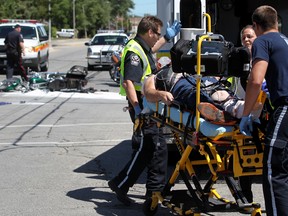 A man is taken away on a stretcher by EMS Paramedics after he was stuck by a minivan while riding a motorcycle at George Avenue and Wyandotte Street East in Windsor, Ont., Monday, Aug. 6, 2012. (DAX MELMER/The Windsor Star)