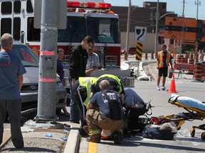 A man is tended to by EMS Paramedics and Windsor firefighters after he was stuck by a minivan while riding a motorcycle at George Avenue and Wyandotte Street East, Monday, Aug. 6, 2012. (DAX MELMER/The Windsor Star)
